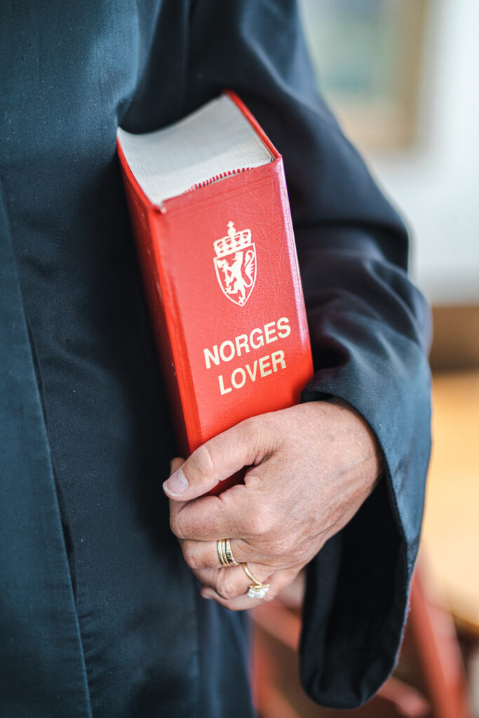 Miljøfotografi av en person som holder Norges Lover i venstre arm
